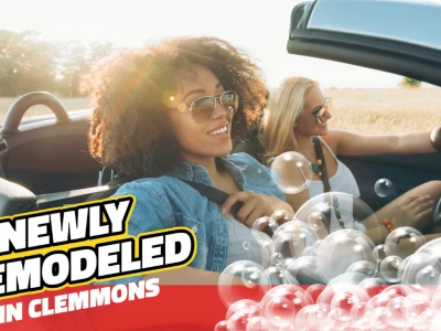 Two women smiling driving a clean car with bubbles. Text reads: "Newly Remodeled in Clemmons"