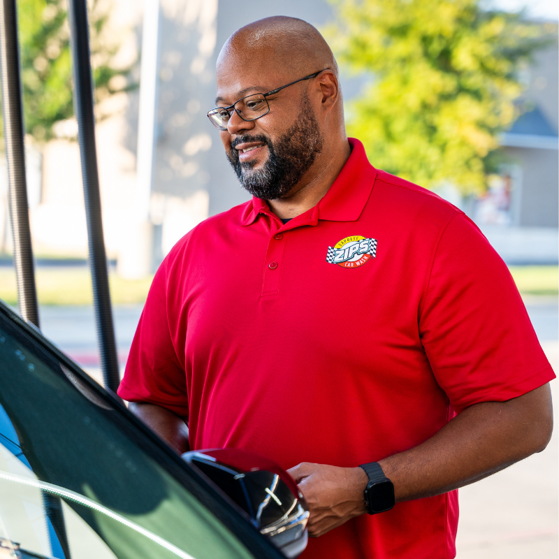 A ZIPS Car Wash employee smiles as he helps a customer